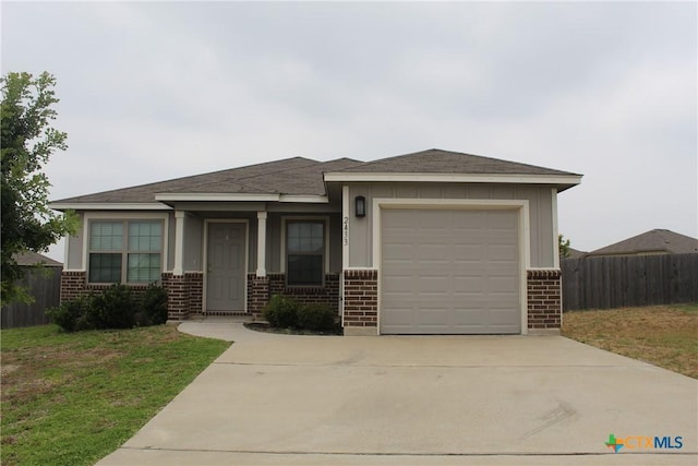 view of front of property featuring a garage, brick siding, and fence