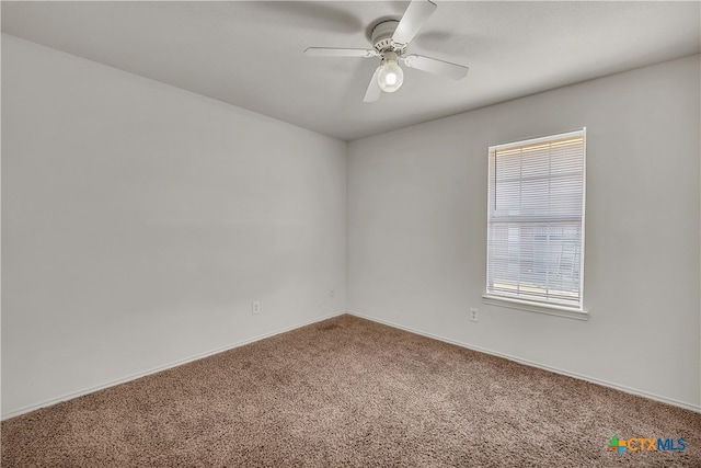 carpeted spare room featuring a wealth of natural light and ceiling fan