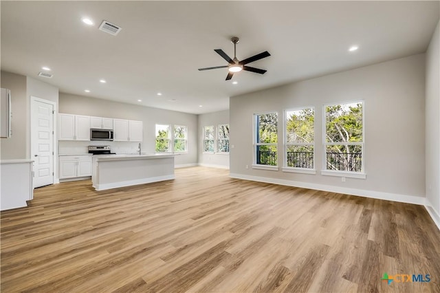 unfurnished living room featuring ceiling fan, sink, and light hardwood / wood-style flooring