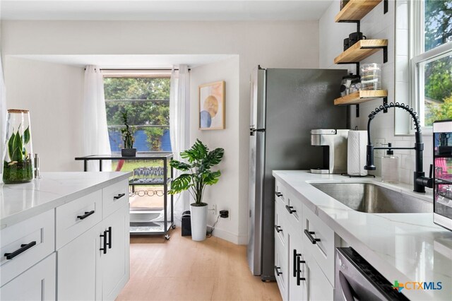 1107 Chesapeake Dr, Austin, TX 78758 - kitchen with open shelves, a sink, light stone countertops, light wood finished floors, and baseboards