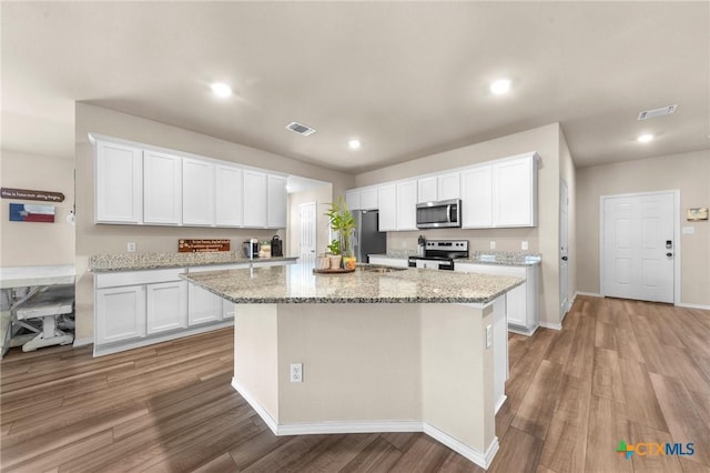 kitchen featuring light wood-type flooring, stainless steel appliances, white cabinets, and a kitchen island