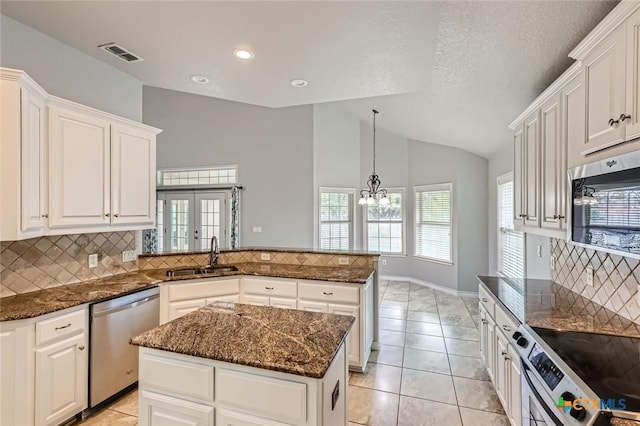 503 Wilderness Way, New Braunfels, TX 78132 - kitchen with appliances with stainless steel finishes, lofted ceiling, a peninsula, decorative backsplash, and white cabinetry