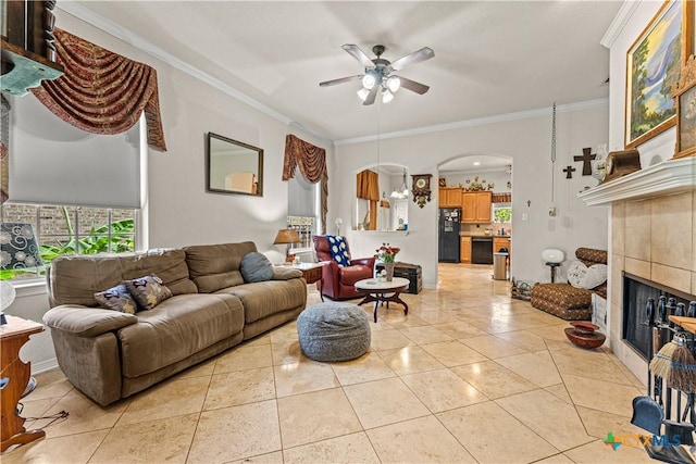 living area featuring light tile patterned floors, arched walkways, a tiled fireplace, and ornamental molding