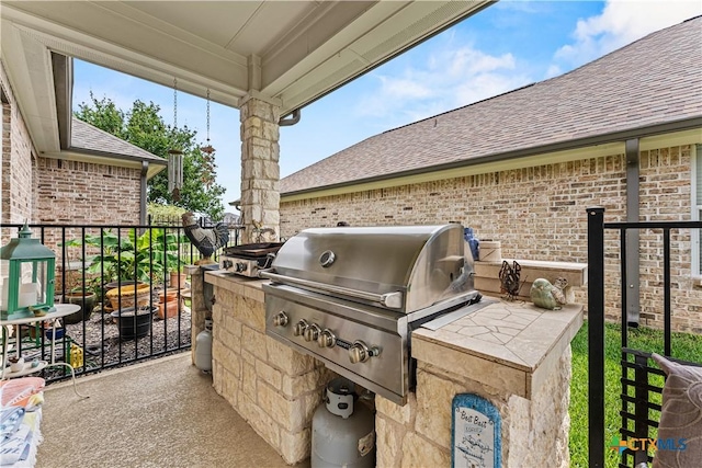 view of patio with exterior kitchen, area for grilling, and fence