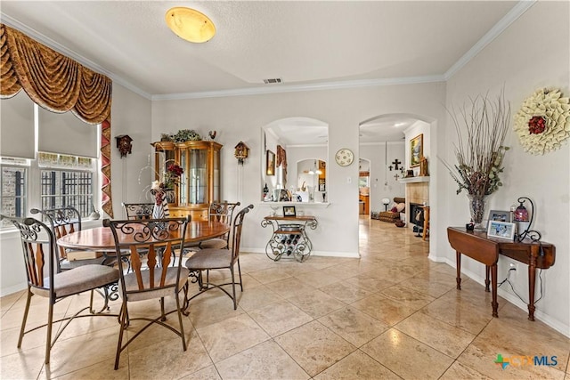 dining space featuring a fireplace, baseboards, and crown molding