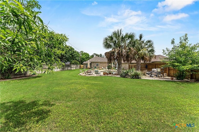 view of yard with a fenced backyard, a fire pit, and a patio