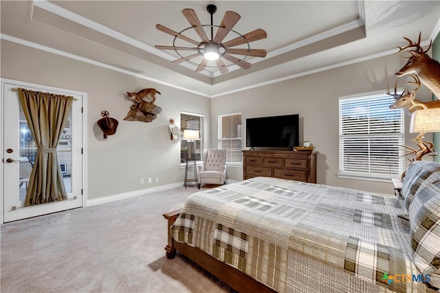 carpeted bedroom featuring a raised ceiling, multiple windows, baseboards, and ornamental molding