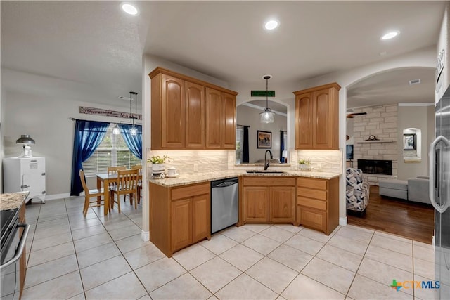 kitchen featuring a sink, light tile patterned flooring, a fireplace, decorative backsplash, and dishwasher