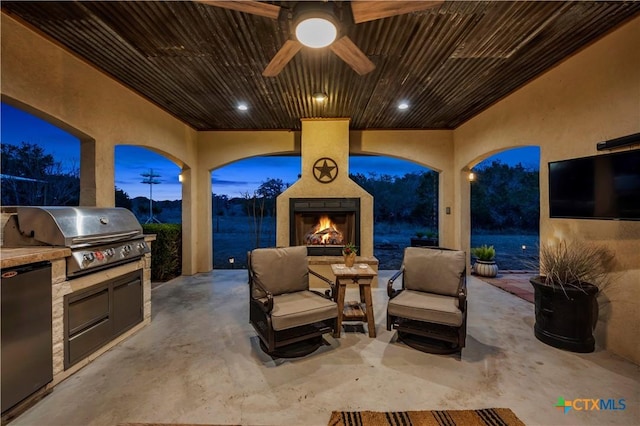 view of patio / terrace with area for grilling, exterior kitchen, a ceiling fan, and an outdoor living space with a fireplace