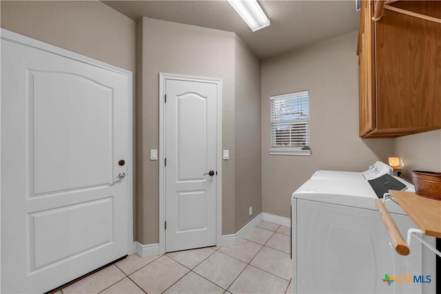 clothes washing area with separate washer and dryer, light tile patterned floors, cabinet space, and baseboards