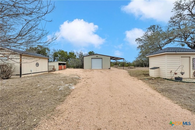 view of yard with driveway, a detached garage, and an outdoor structure