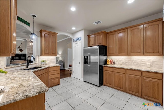 kitchen featuring visible vents, a sink, decorative light fixtures, arched walkways, and stainless steel fridge with ice dispenser