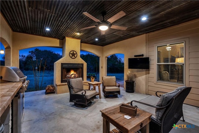 view of patio / terrace with area for grilling, an outdoor living space with a fireplace, and a ceiling fan