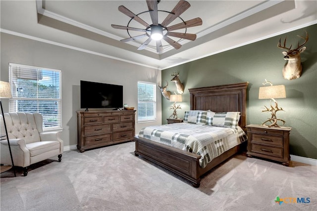 bedroom with a tray ceiling, crown molding, baseboards, light colored carpet, and ceiling fan