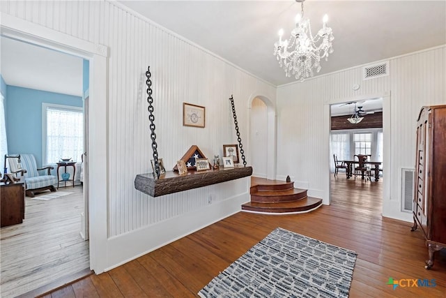 corridor featuring arched walkways, a chandelier, a healthy amount of sunlight, and hardwood / wood-style floors