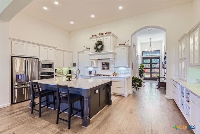 108 Rainbow Valley Trl, San Marcos, TX 78666 - kitchen featuring appliances with stainless steel finishes, arched walkways, light countertops, white cabinets, and backsplash