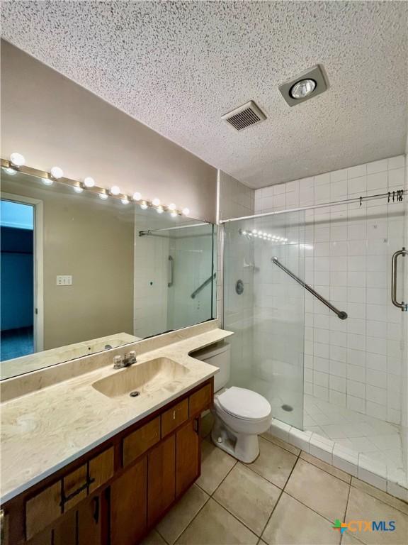 bathroom featuring visible vents, a stall shower, vanity, a textured ceiling, and tile patterned floors