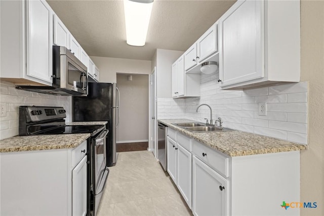 kitchen with white cabinets, decorative backsplash, stainless steel appliances, and a sink