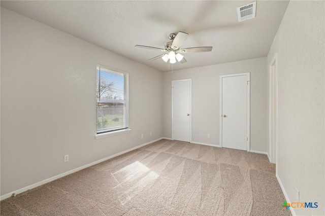 unfurnished bedroom with light carpet, baseboards, visible vents, and a ceiling fan