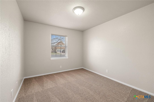 empty room featuring a textured ceiling, a textured wall, carpet, and baseboards