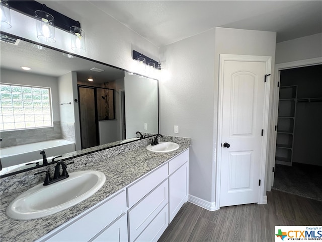 bathroom with wood-type flooring, vanity, and plus walk in shower