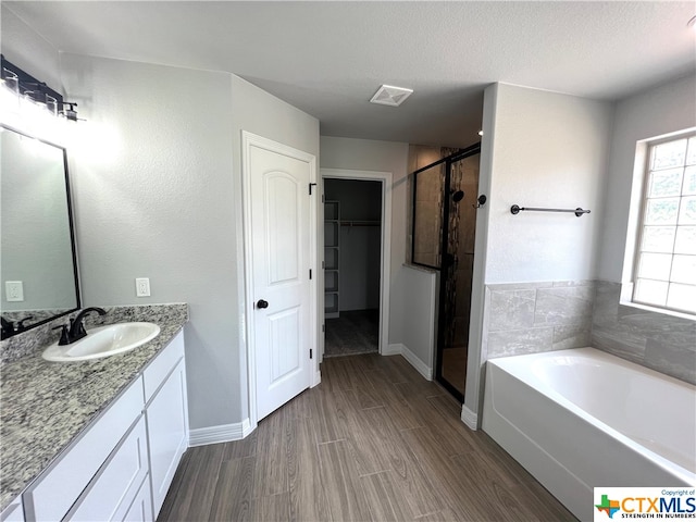 bathroom featuring independent shower and bath, wood-type flooring, vanity, and a textured ceiling