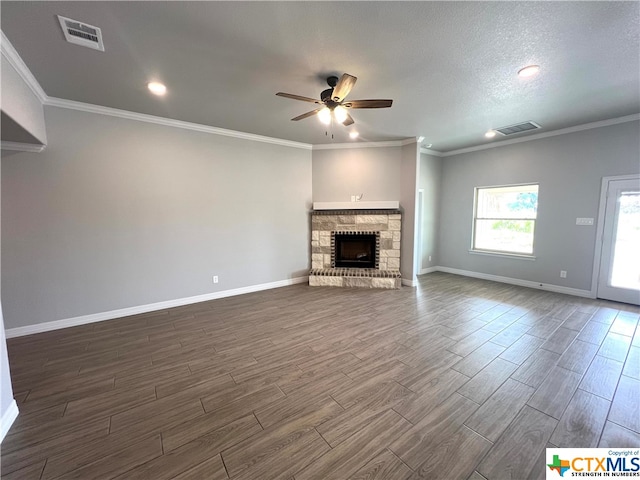 unfurnished living room with a stone fireplace, a textured ceiling, dark hardwood / wood-style floors, ceiling fan, and crown molding