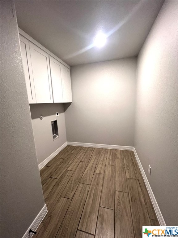 laundry area with dark wood-type flooring, cabinets, and electric dryer hookup