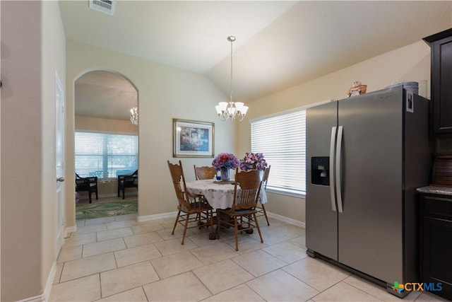 dining area with healthy amount of natural light, a chandelier, arched walkways, light tile patterned floors, and vaulted ceiling