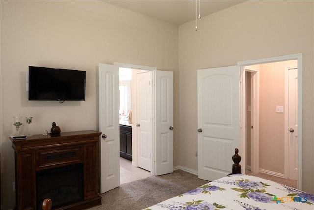 bedroom featuring light carpet, connected bathroom, and vaulted ceiling
