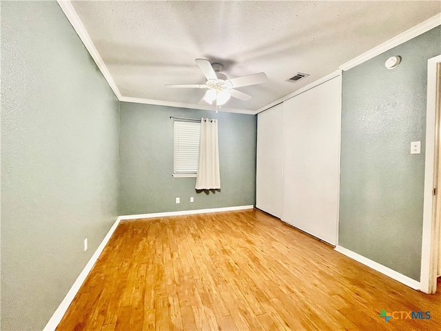 empty room featuring ceiling fan, wood-type flooring, and ornamental molding