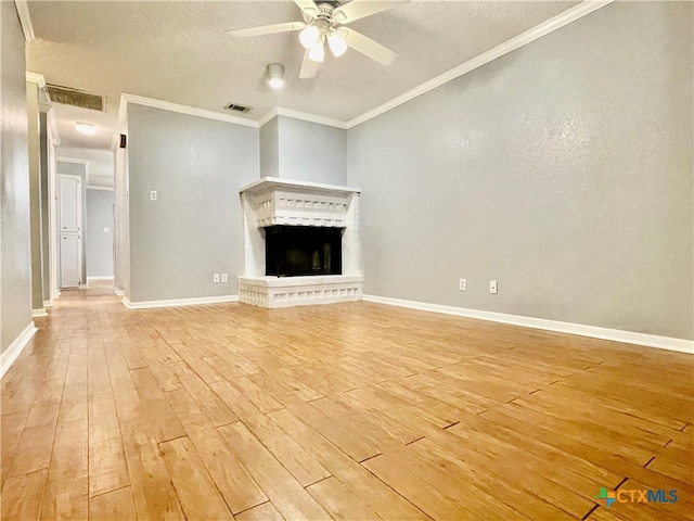 unfurnished living room featuring a brick fireplace, light hardwood / wood-style floors, ceiling fan, and crown molding