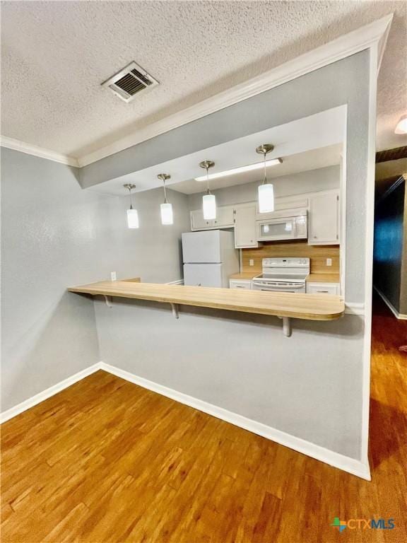 409 Versailles St, Victoria, TX 77904 - kitchen featuring white appliances, crown molding, a peninsula, baseboards, and wood finished floors