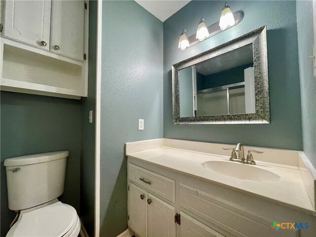 bathroom featuring vanity, toilet, and an enclosed shower