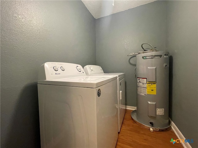 laundry area featuring separate washer and dryer, water heater, a textured ceiling, and light wood-type flooring