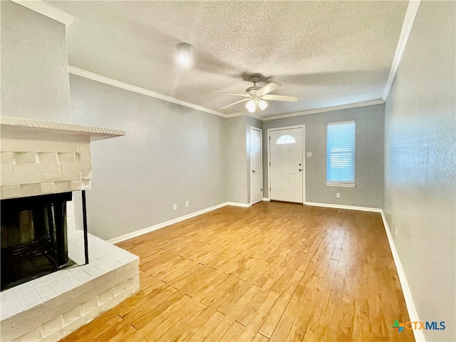 unfurnished living room featuring a brick fireplace, wood-type flooring, ornamental molding, and ceiling fan