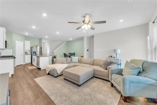 living room featuring ceiling fan, sink, and light hardwood / wood-style floors