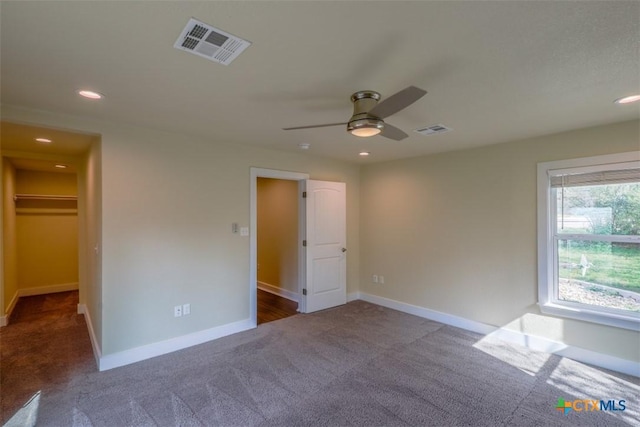 unfurnished bedroom featuring carpet, visible vents, baseboards, and a walk in closet