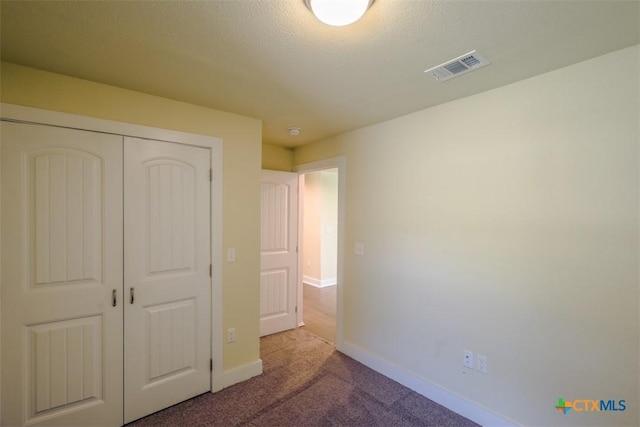 unfurnished bedroom featuring visible vents, baseboards, carpet flooring, and a closet