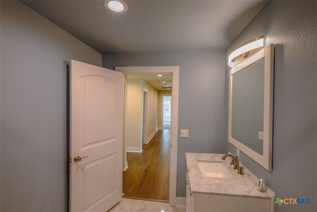 bathroom featuring baseboards, recessed lighting, and vanity