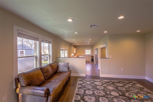 living area featuring dark wood finished floors, visible vents, baseboards, and recessed lighting