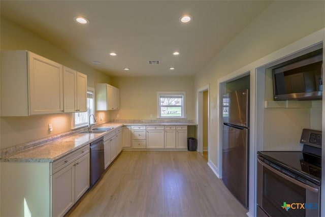 kitchen with a sink, white cabinetry, stainless steel appliances, and light wood-style floors