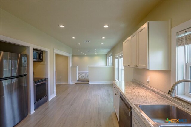 kitchen with recessed lighting, light wood-style floors, appliances with stainless steel finishes, a sink, and white cabinetry