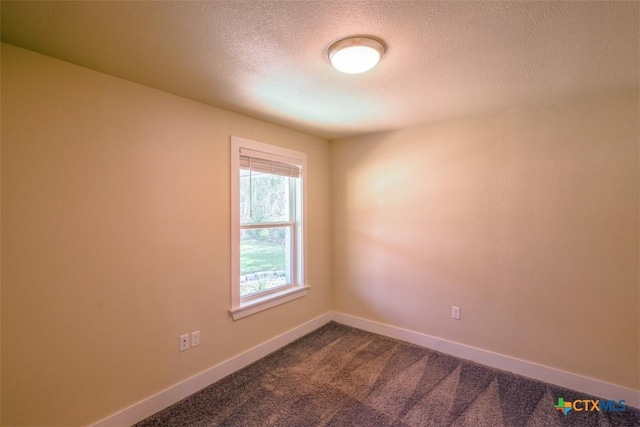 unfurnished room featuring baseboards, dark carpet, and a textured ceiling