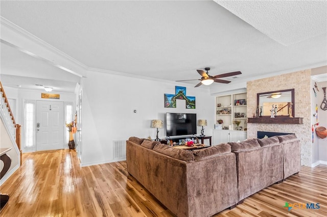 living area featuring light wood-style flooring, baseboards, ornamental molding, and ceiling fan