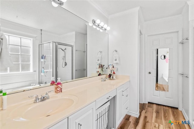 bathroom with double vanity, a sink, a stall shower, and wood finished floors