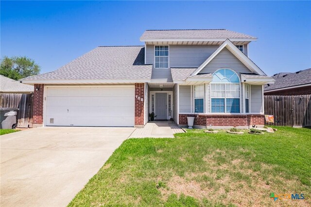 view of front of home with brick siding, a front yard, an attached garage, and fence