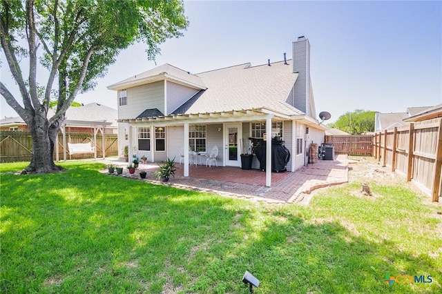 back of house featuring a patio, a yard, a fenced backyard, and a chimney
