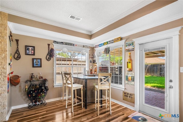 dining area with ornamental molding, visible vents, baseboards, and wood finished floors