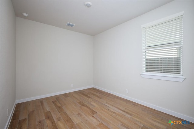 empty room featuring visible vents, light wood finished floors, and baseboards